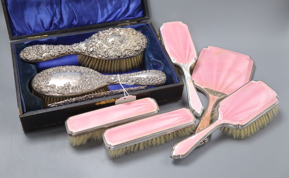 An Edwardian silver backed hair brush and comb set in fitted case, and a five piece pink enamelled silver brush set (a.f.)